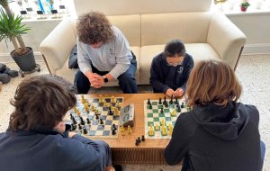 four students of various ages playing chess